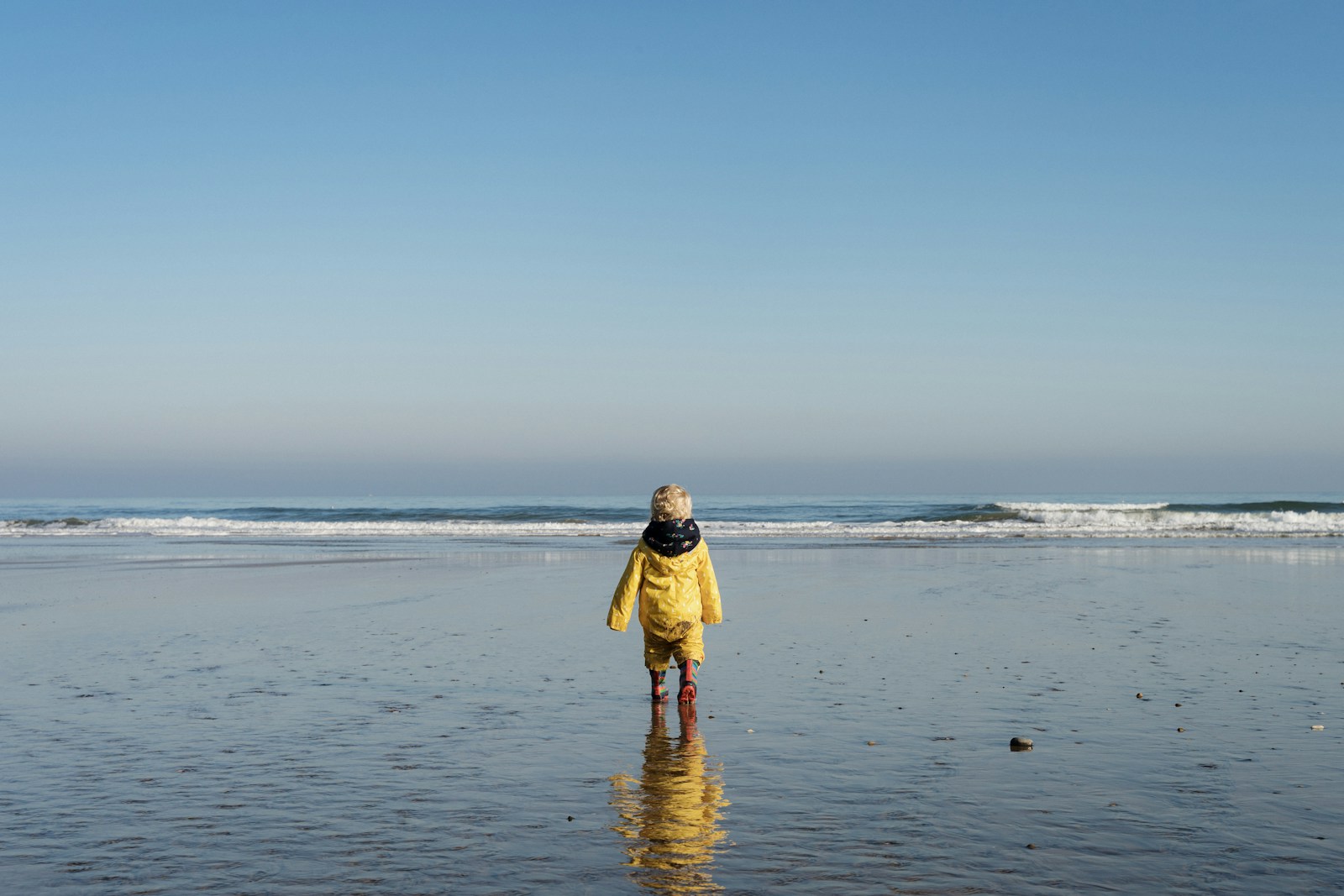 woman in yellow dress walking on beach during daytime